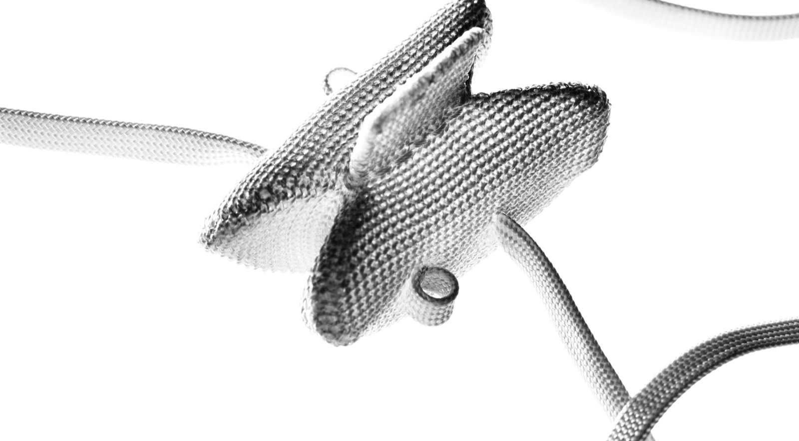 DIAM implant showing its woven polyester covering, central spacer, and attached tethers
