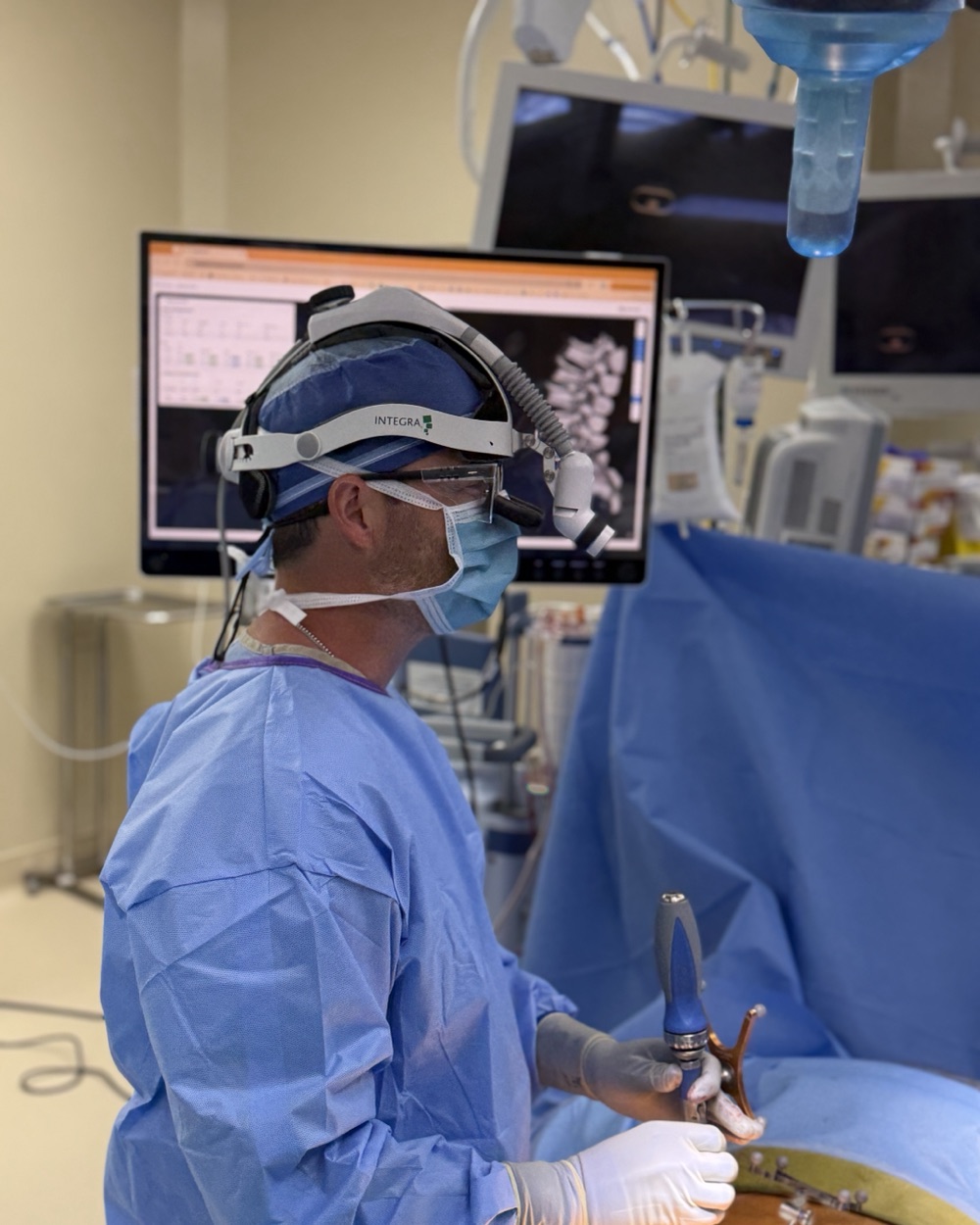 Dr. Jonathan Hobbs in the operating room at Northwest Health Porter with the patient's personalized spine plan on the monitor behind him