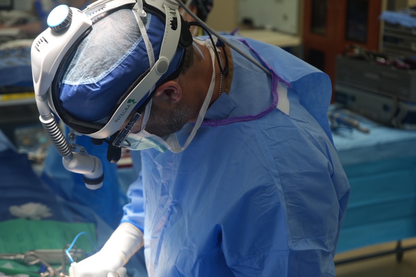 Dr. Hobbs in the operating room wearing a surgical headlight, focused on the surgical field
