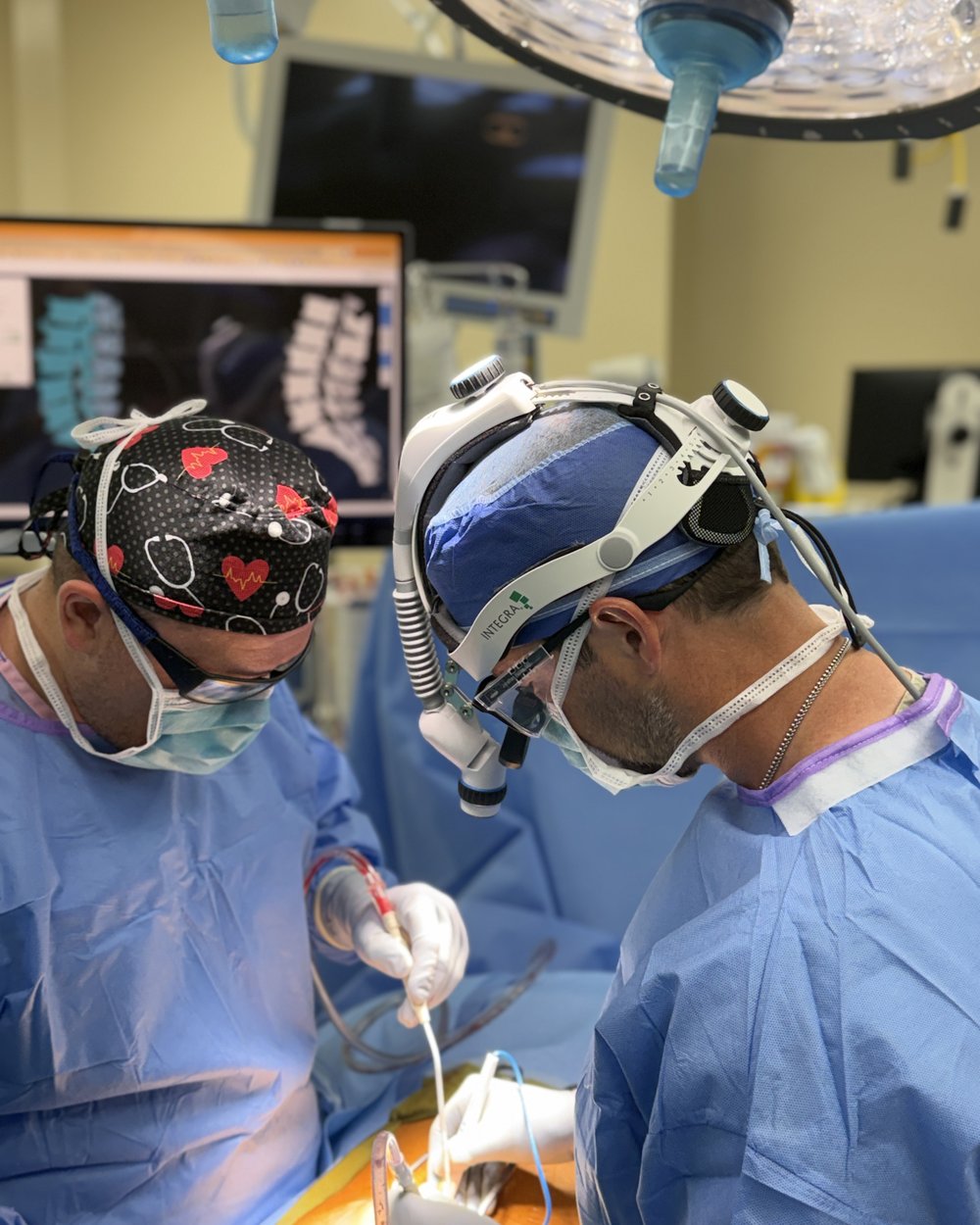 Dr. Hobbs in the operating room with a spine model displayed on the surgical monitor